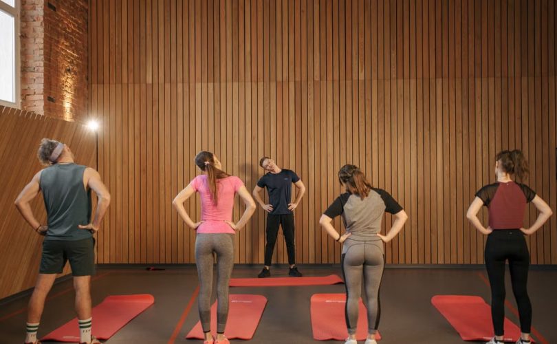 Men and women performing stretching exercises on mats in a fitness class