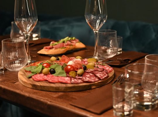 Sophisticated charcuterie board with wine glasses on a wooden table creates a cozy dining ambiance.