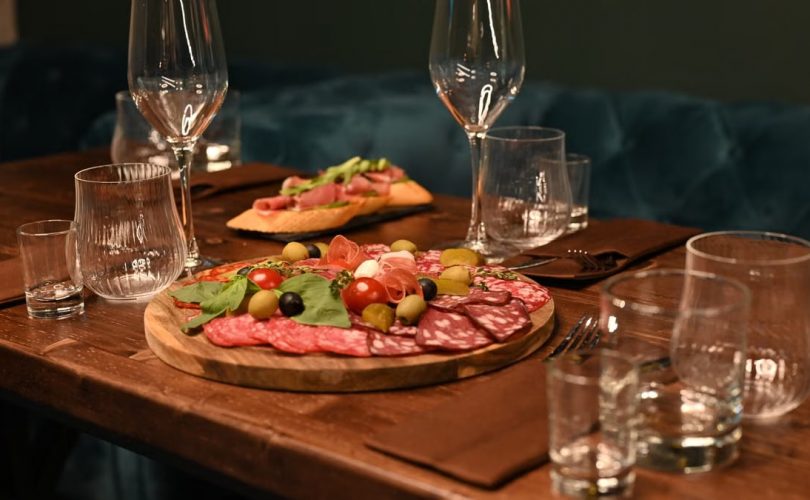 Sophisticated charcuterie board with wine glasses on a wooden table creates a cozy dining ambiance.